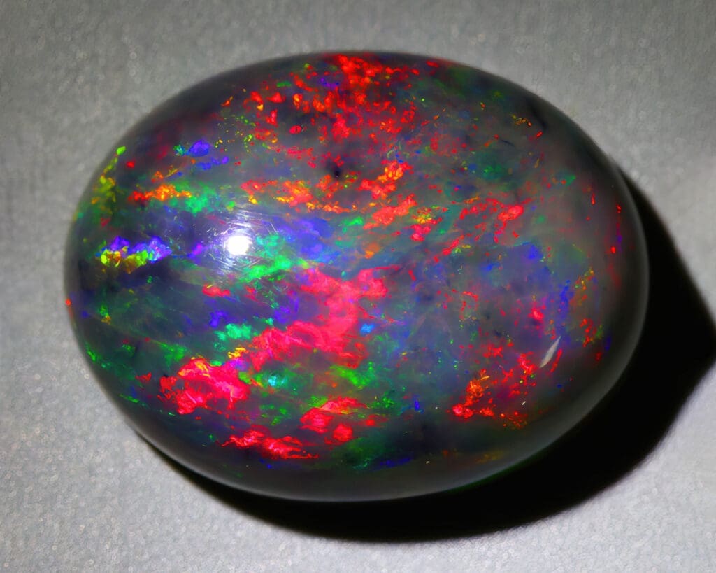 Natural gemstone black opal on gray background